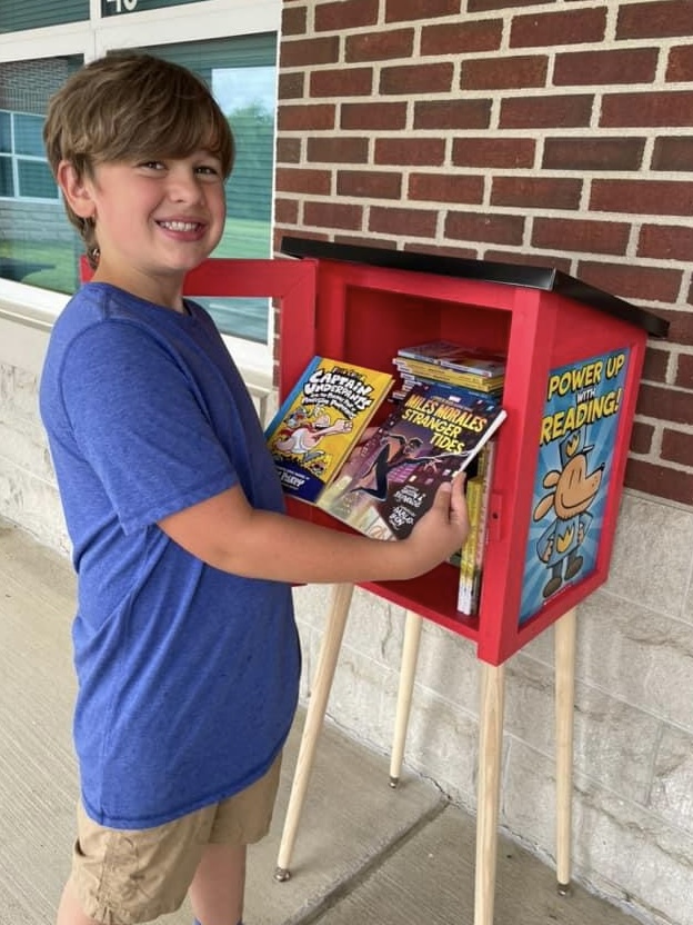 Boy taking books from little library