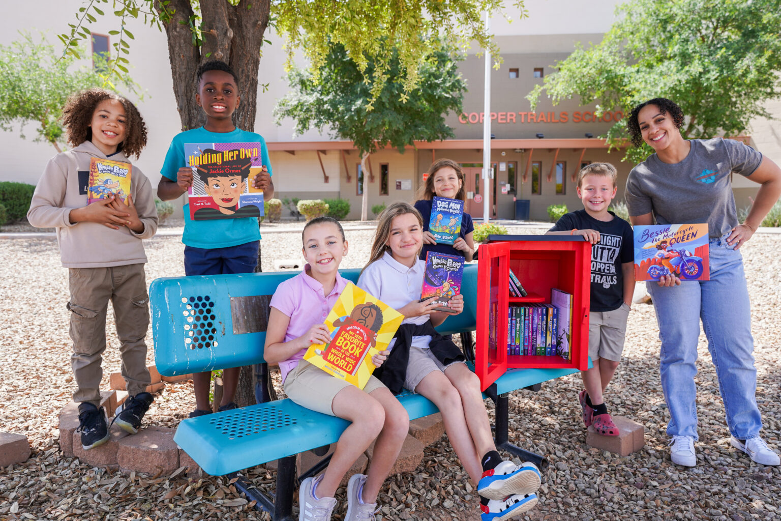 Children holding books by library box
