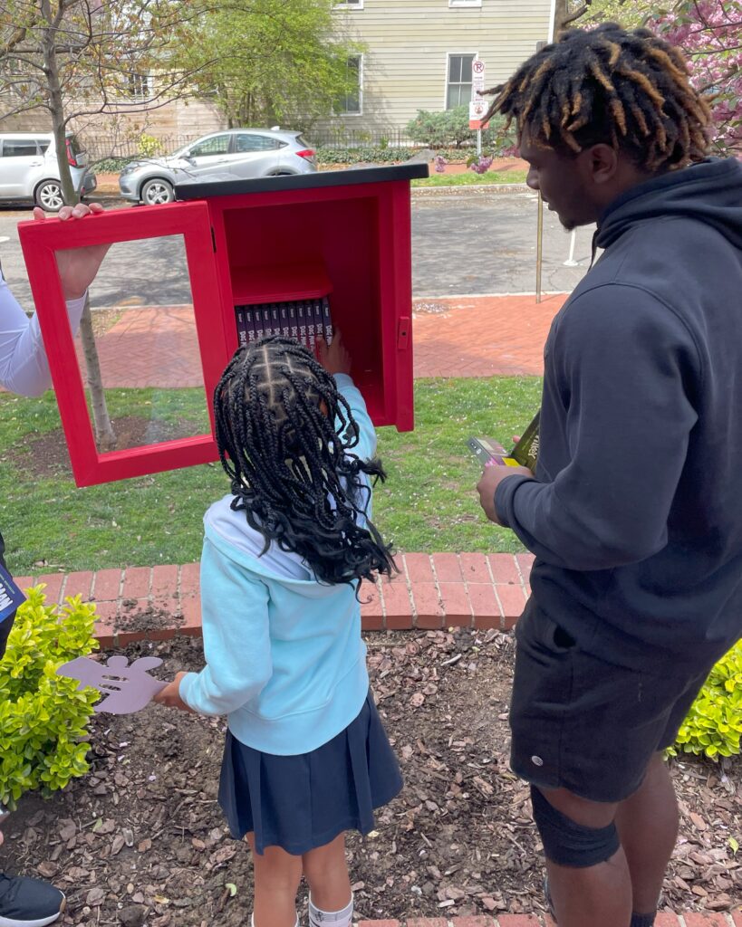 A child looks through a red box little library