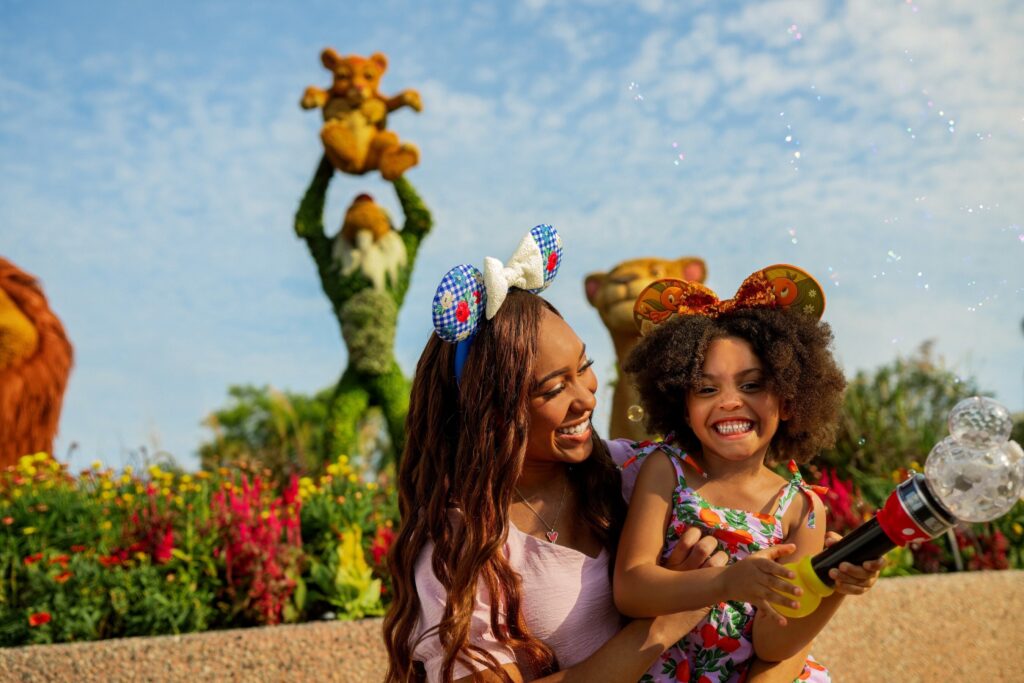 A woman and child stand in front of a Disney-themed topiary in this promotional image for Walt Disney World