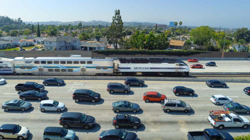 A Metrolink train cruises past cars on the on 10 freeway in Los Angeles in this undated promotional image from Metrolink.
