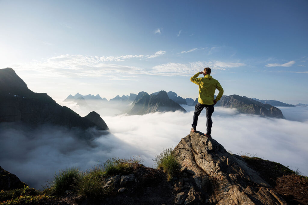 A man gazes out at the horizon from the peak of a mountain in Lofoten, Norway