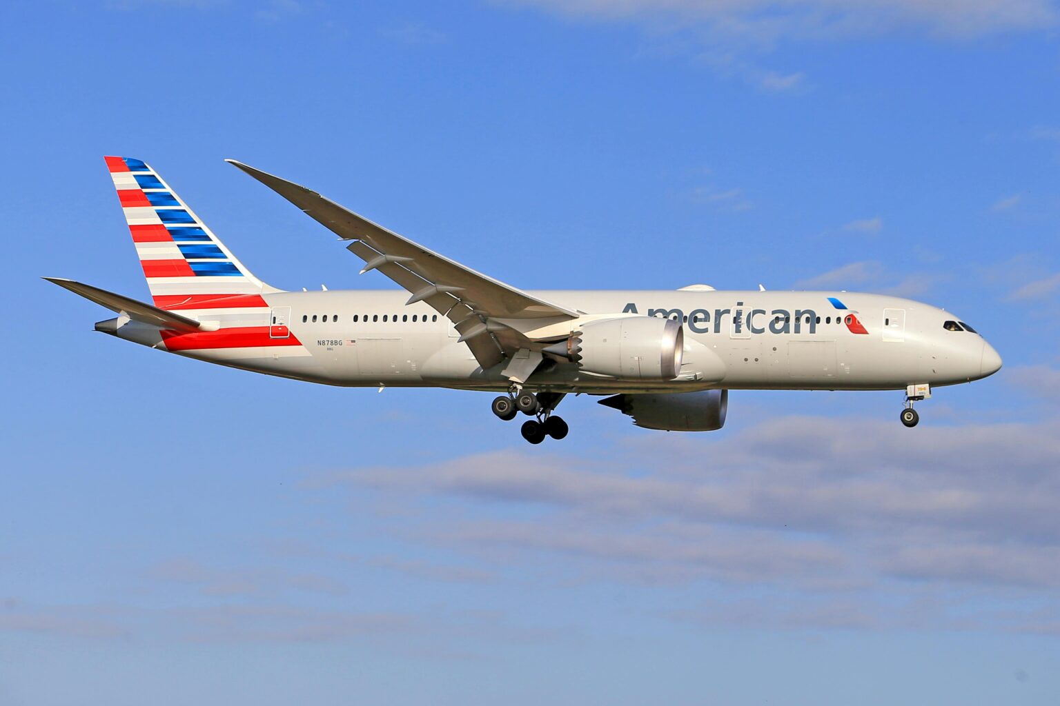 An American Airlines plane flies in the sky over a blue background