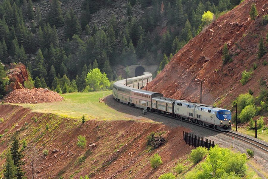 A long-distance Amtrak train navigates a mountain pass in this undated promotional image. (Amtrak)