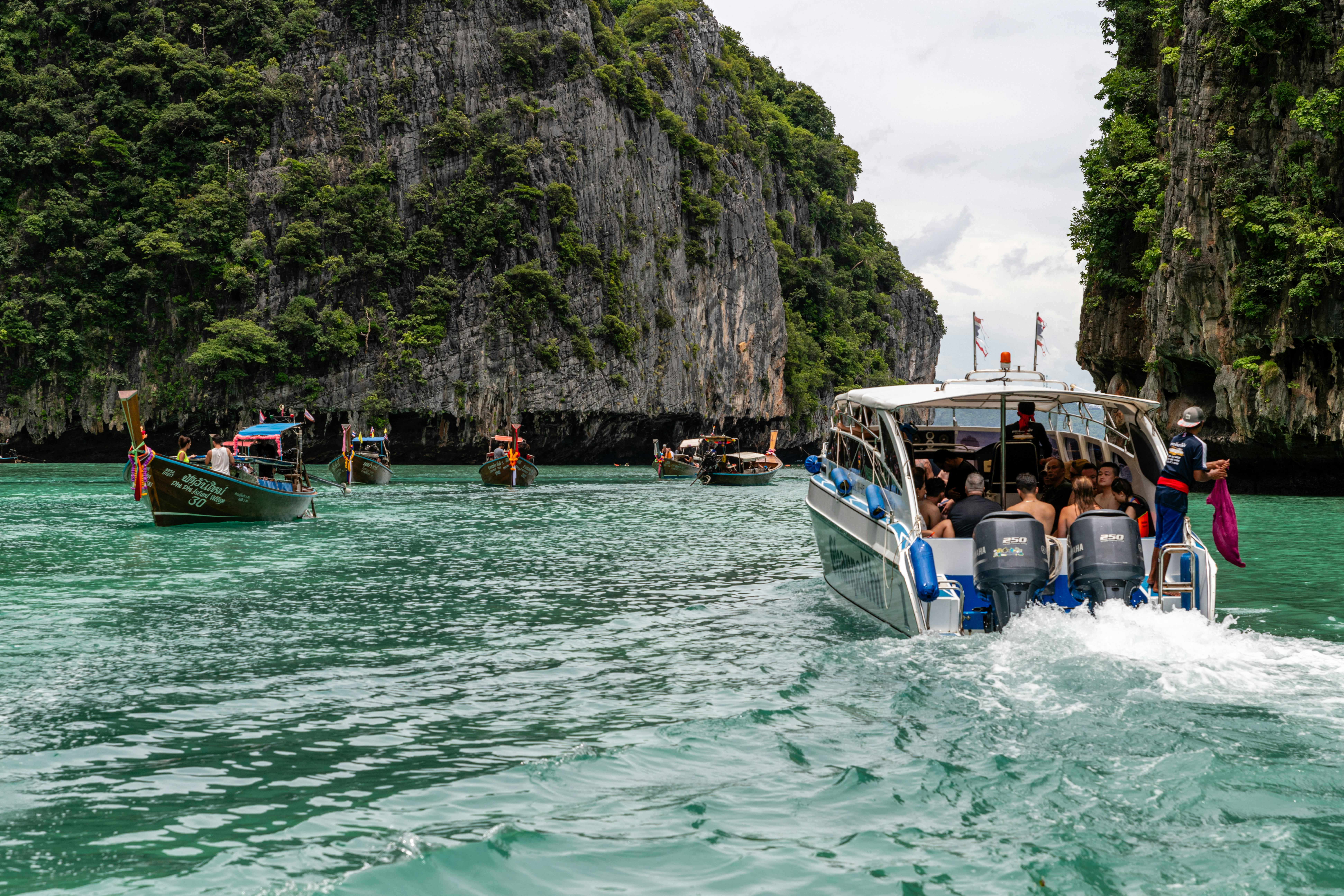 Passengers ride in a boat between two large cliffside in Phuket, Thailand