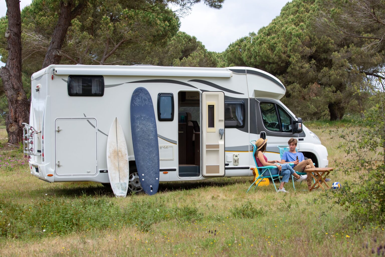 A couple relaxed next to an RV during a camping excursion. (Pexels.com)