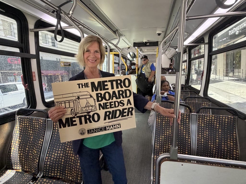Los Angeles County Supervisor and LA Metro Board Member Janice Hahn poses with a sign that reads "The Metro Board Needs a Metro Rider" in this photo from July 2026. (Janice Hahn's Office)